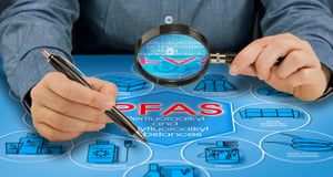 Person examining a PFAS infographic with a magnifying glass.