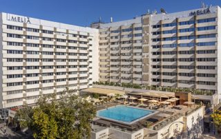 Exterior view of the Meliá Sevilla hotel with a central outdoor pool.