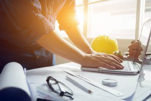 Man working with laptop and blueprints