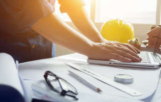 Man working with laptop and blueprints