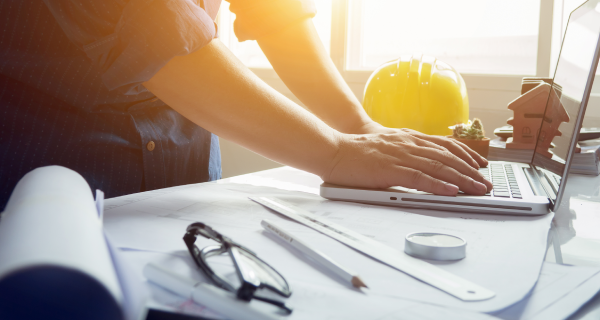 Man working with laptop and blueprints